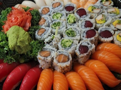 a plate of sushi and vegetables on a table.