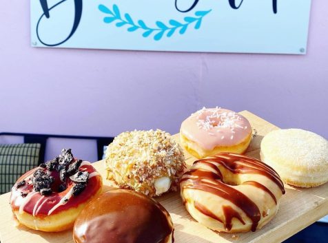 a wooden tray topped with lots of donuts.