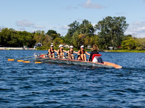 a group of people rowing a boat on a lake.