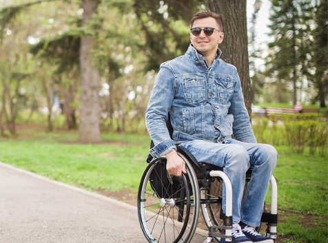 a man sitting in a wheel chair in a park.