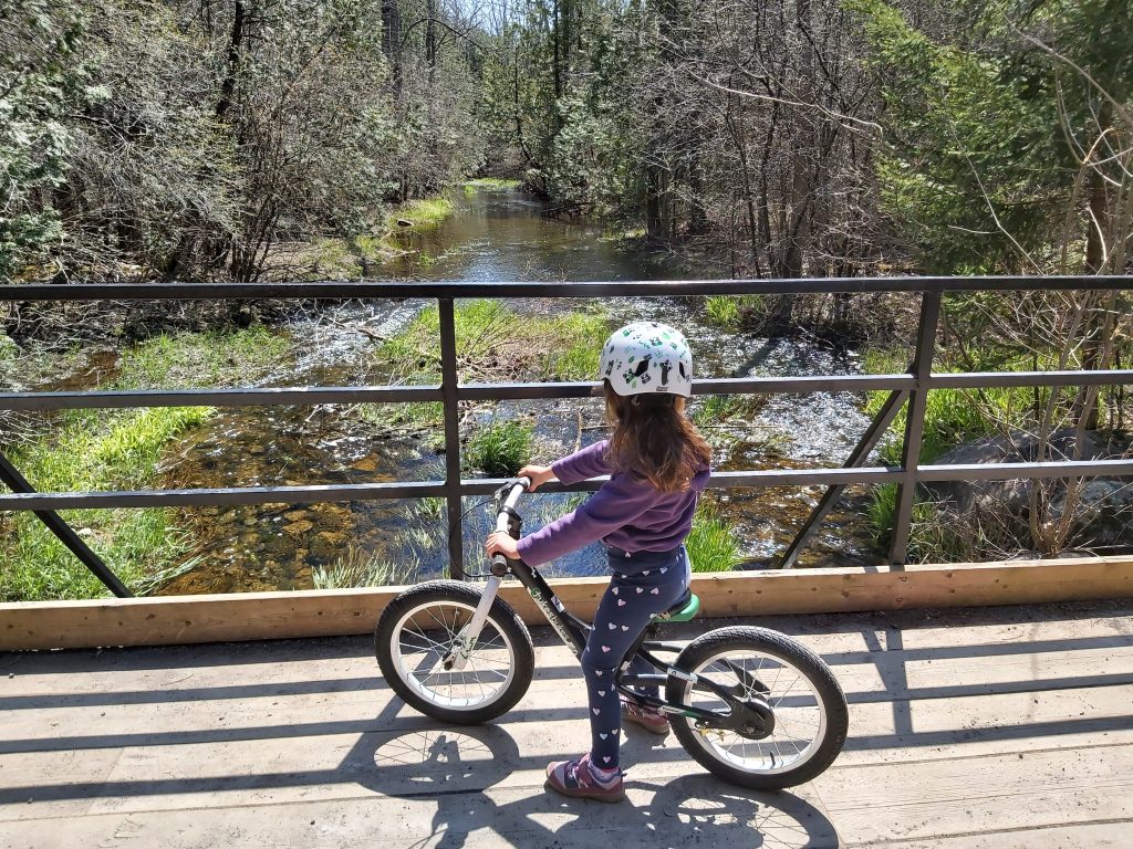 a little girl riding a bike on a bridge.