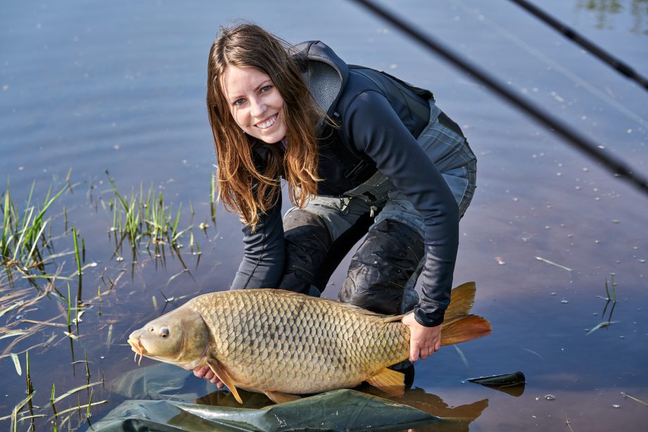 a woman holding a fish in a body of water.
