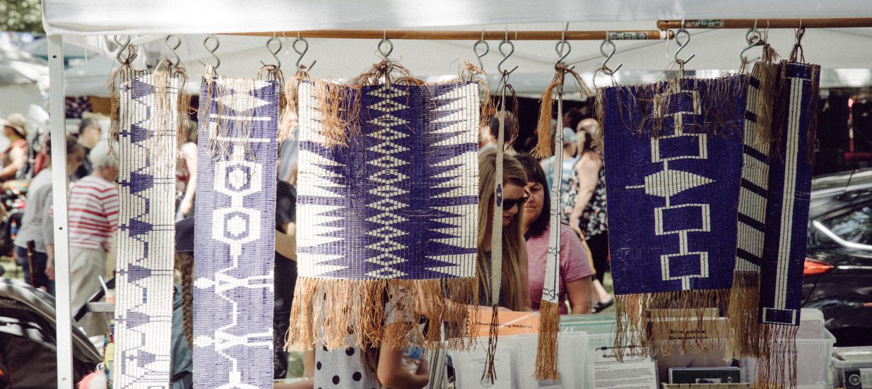 a group of people standing next to a display of handmade items.