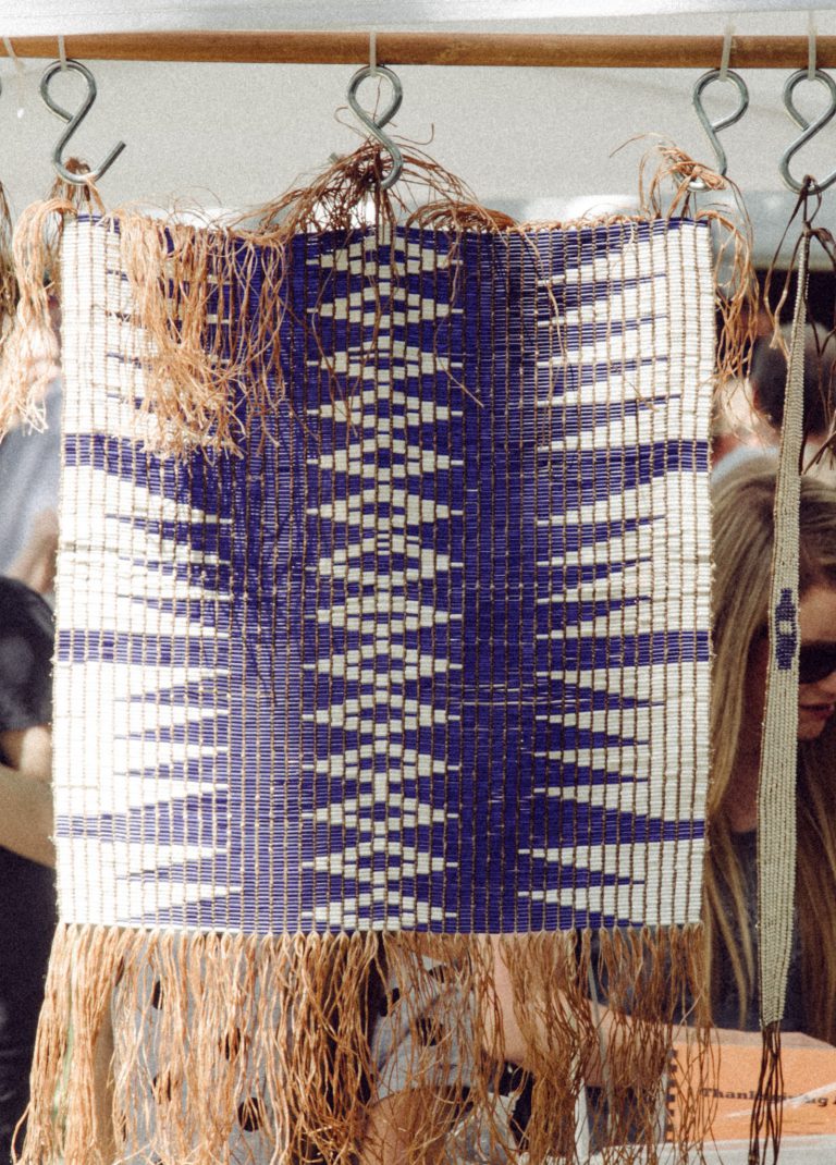 a group of people standing around a weaving project.