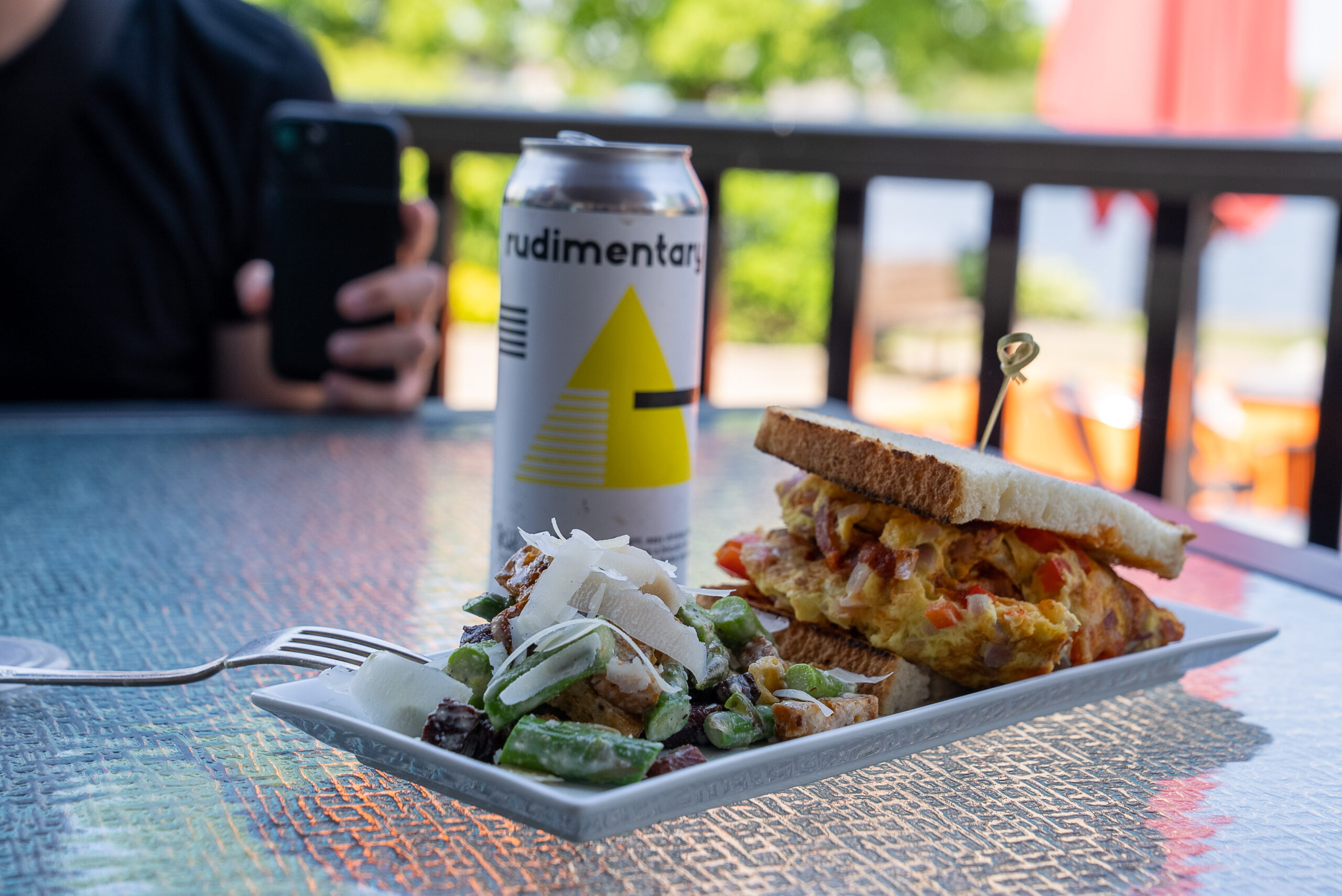a sandwich, salad and can of craft beer sitting on a patio table