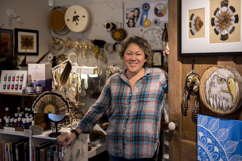 a woman standing in a room with many items on the wall.