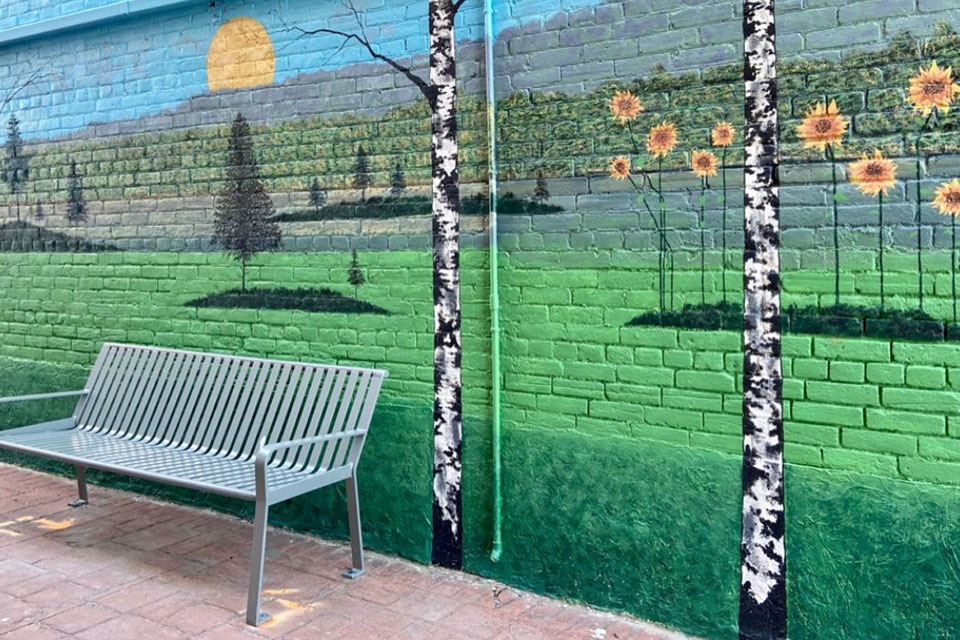 a bench sitting in front of a painted wall.