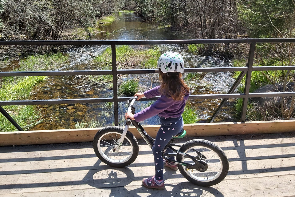 a little girl riding a bike on a bridge.