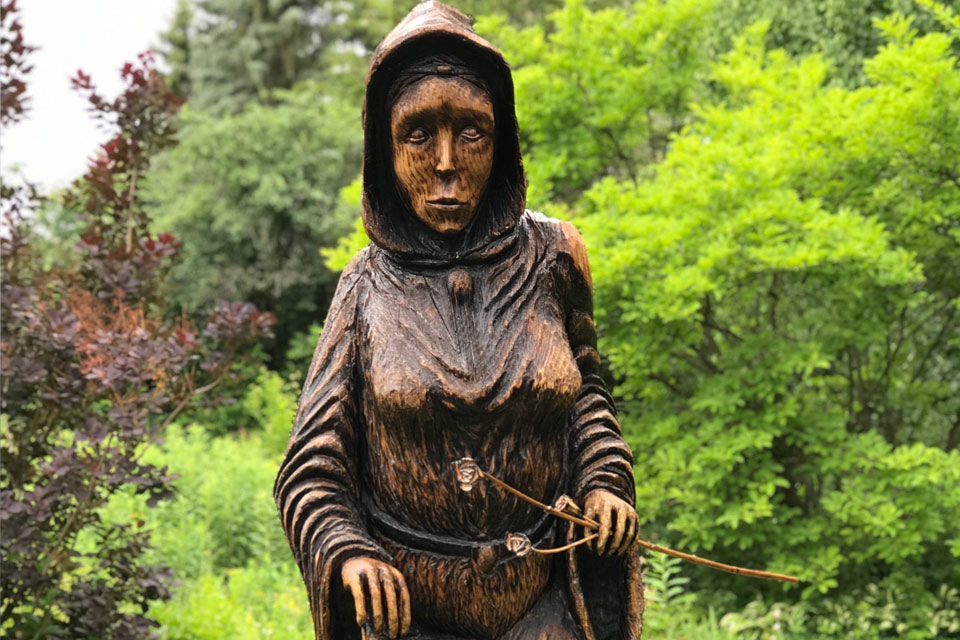 a statue of a woman holding a stick.