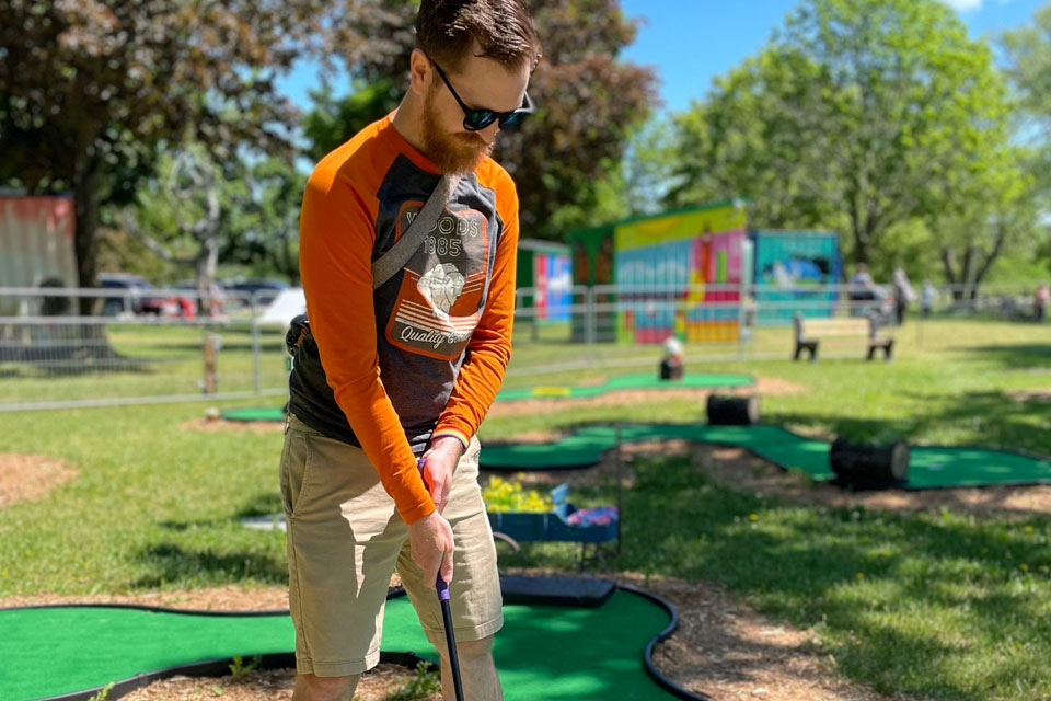 a man is playing mini golf in a park.