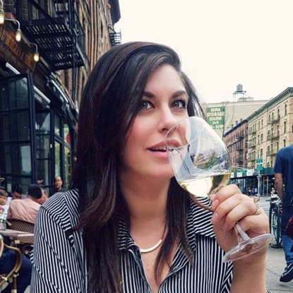 a woman holding a glass of wine in her hand.