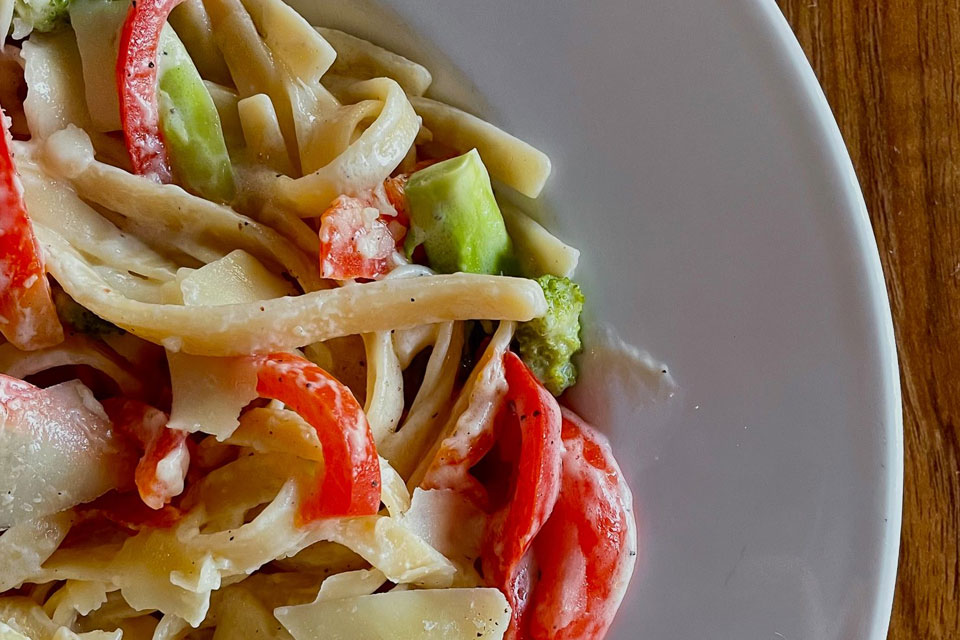 a white plate topped with pasta and veggies.