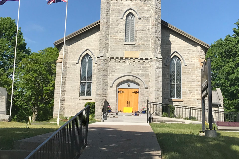 a church with a yellow door and two flags flying in the wind.
