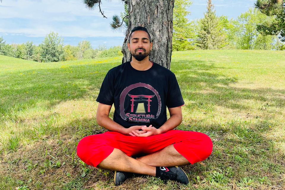 a man in a black shirt and red pants meditates in front of a.