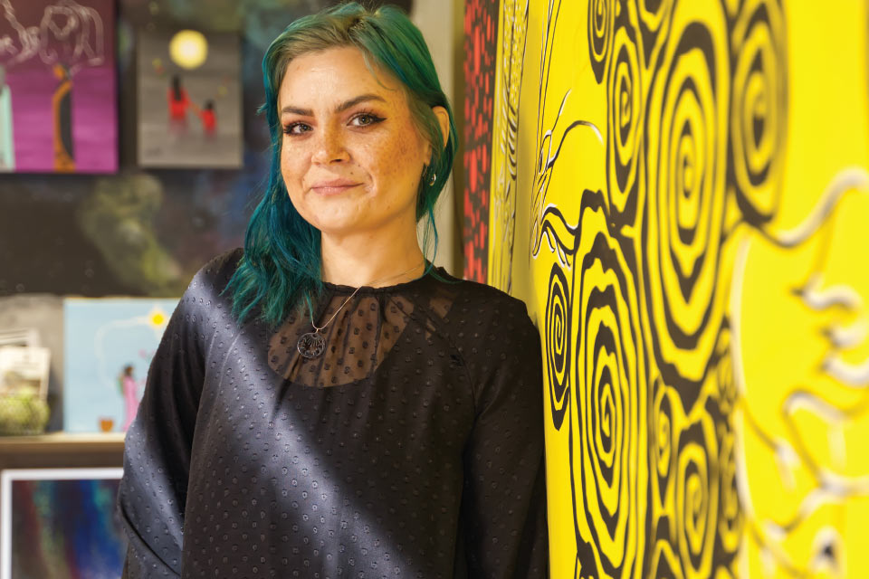 a woman with green hair standing in front of a yellow wall.