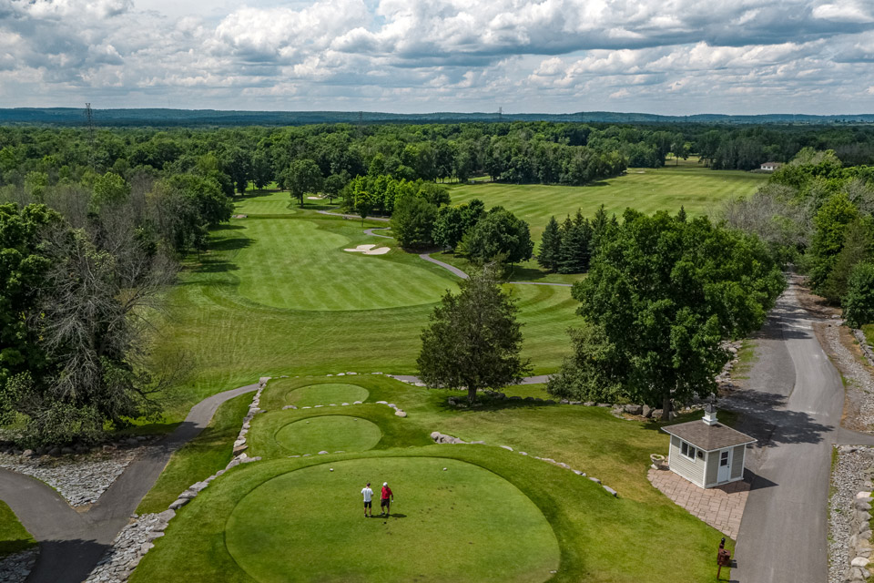 an aerial view of a golf course with trees in the background.