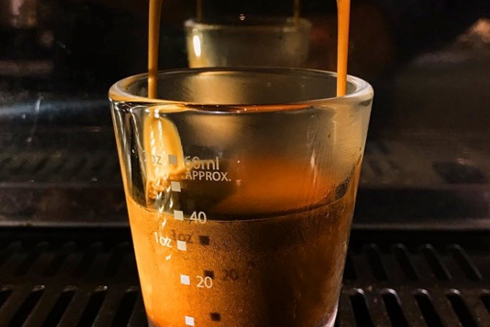 a cup of coffee being poured into an espresso machine.