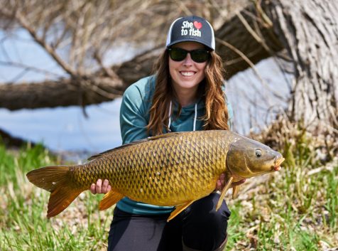 a woman holding up a large carp.
