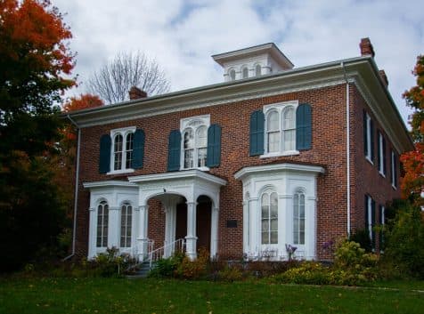a brick house with green shutters.