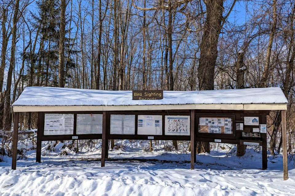 a snow covered trail station in a wooded area.