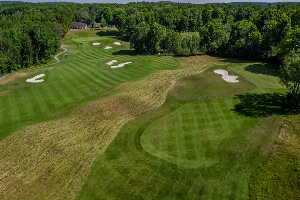 an aerial view of a golf course in the woods.