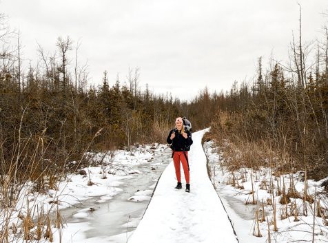 a woman standing on a boardwalk in the snow.