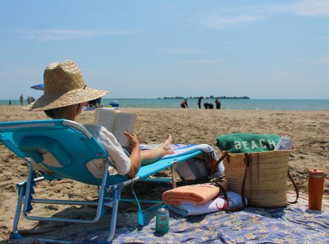 A person reading a book on a beach.