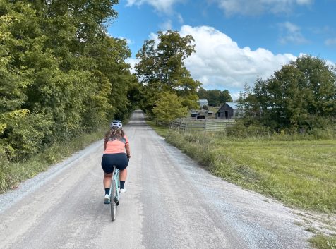 A woman on a bike riding down a gravel road