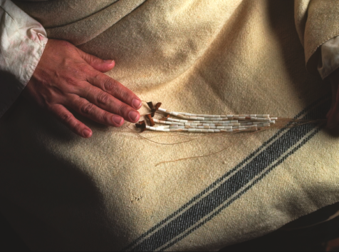 a person's lap wth strings of beaded wampum in their hands