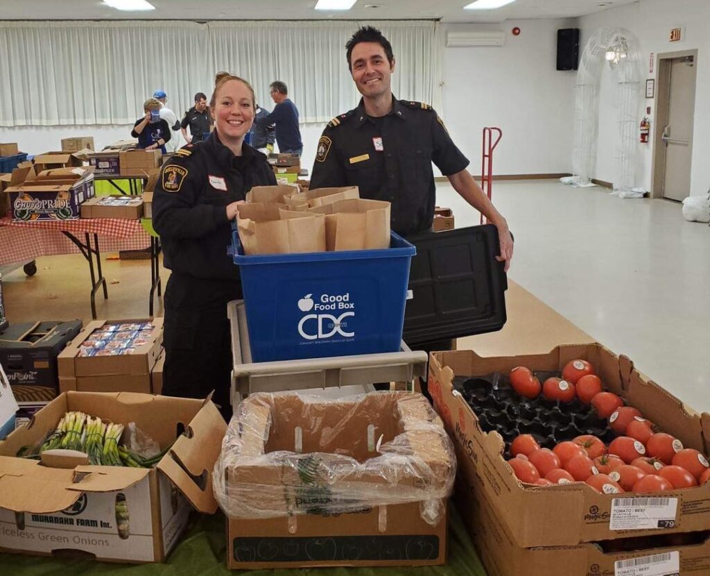 a man and woman who are firefighters packing food donation bozes