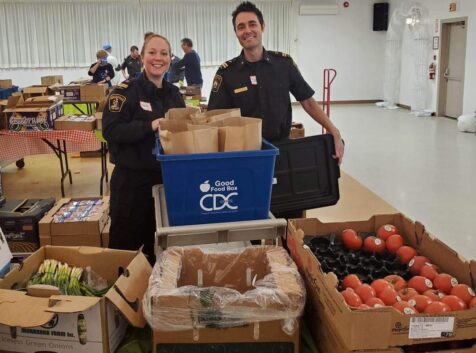 a man and woman who are firefighters packing food donation bozes