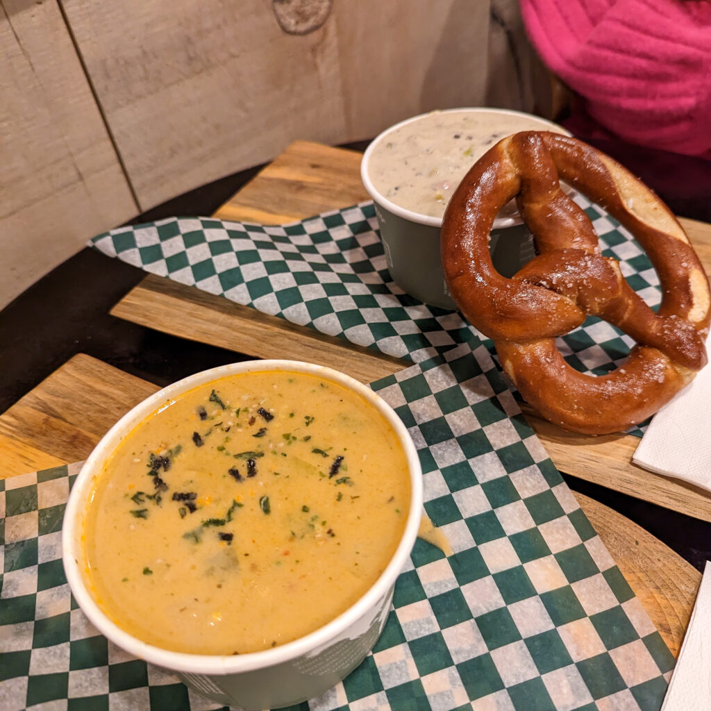 two bowls of soup and a soft pretzel