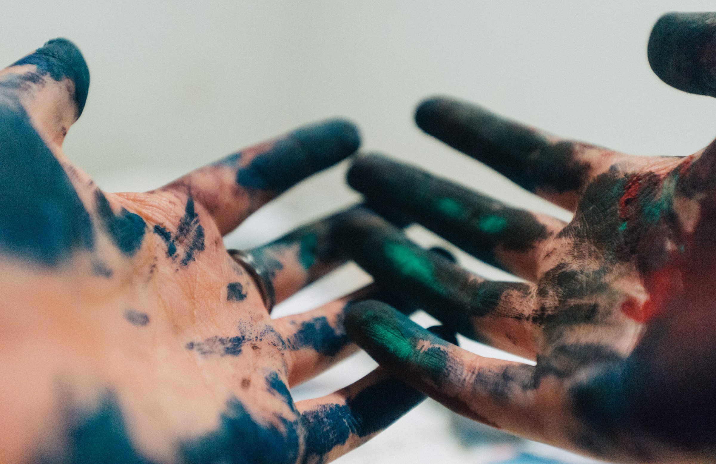 picture of adults' hands covered in green paint. Appear to be from finger painting