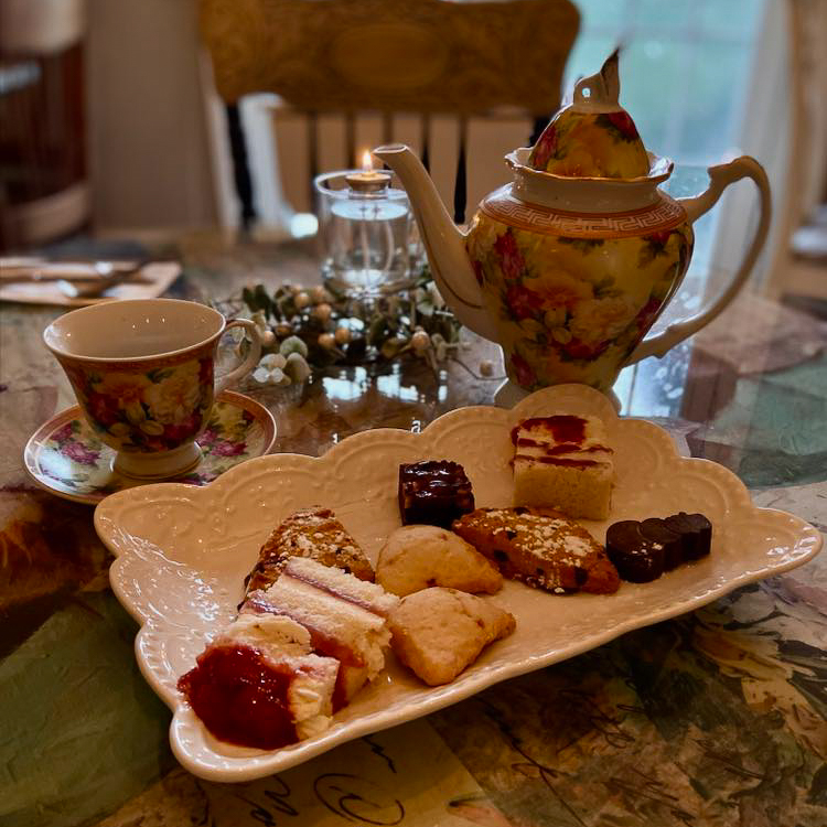 a tea pot, teacups and pastries on a table