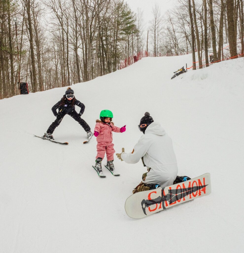 a man and woman skiing and snowboarding with a small child