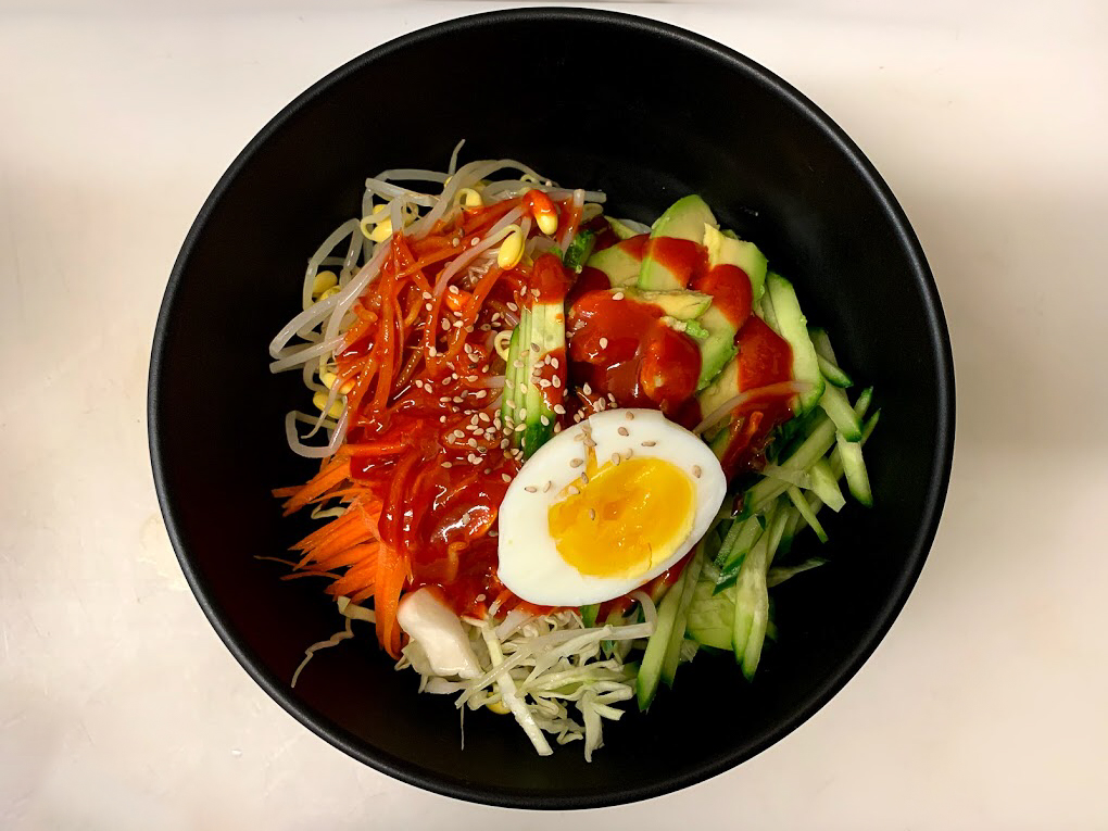 a dish of korean food with acovado, noodles, sprouts, vegetables and egg