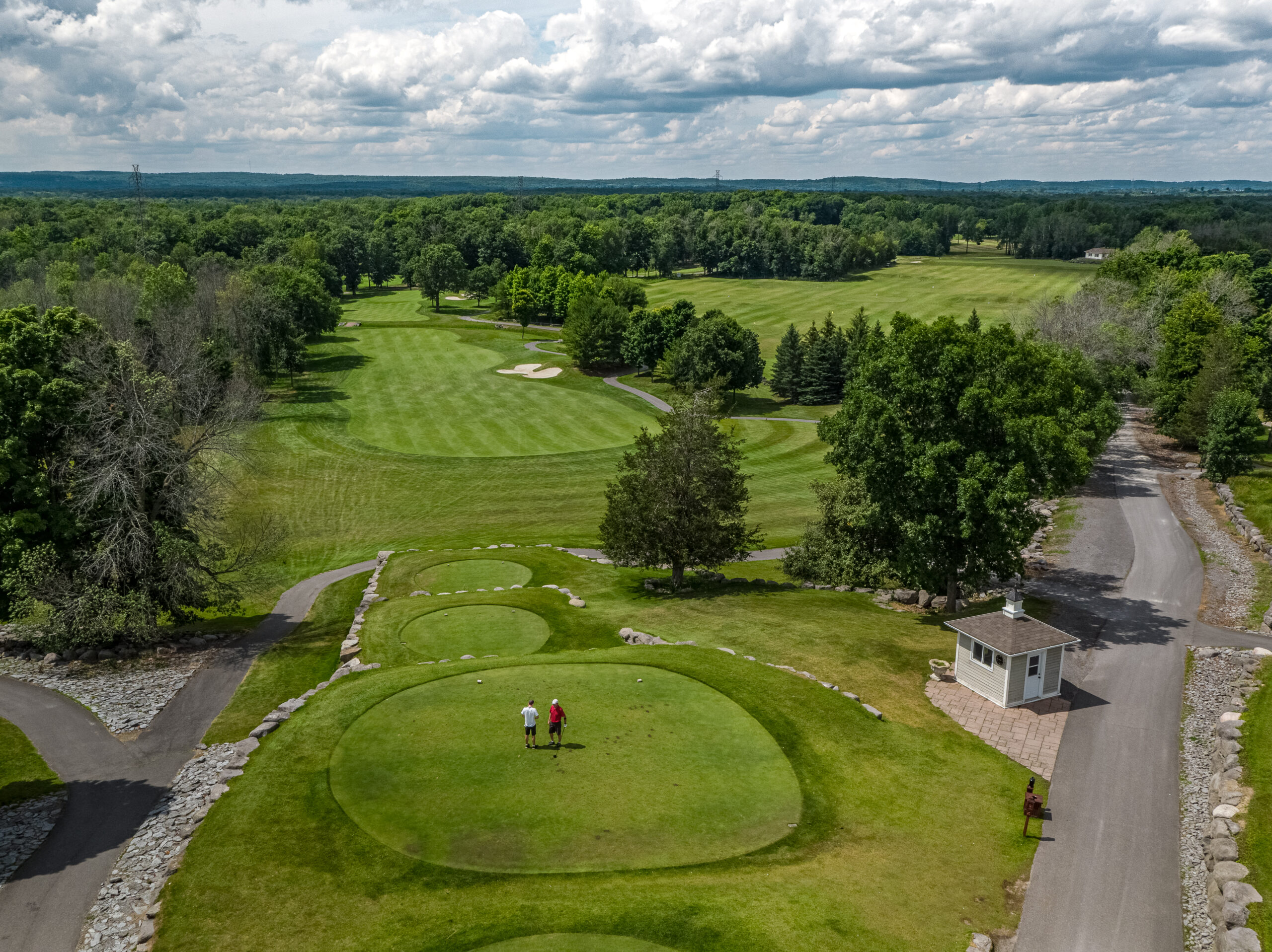 aerial view of a golf course with wooded areas around the green