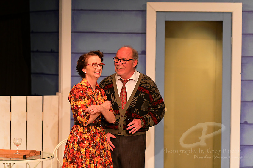 a man and woman in old-fashioned clothing on stage at a community theatre