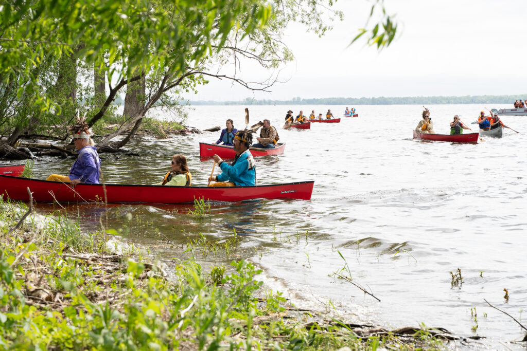 Several people in canoes paddling on to the shore of a bay