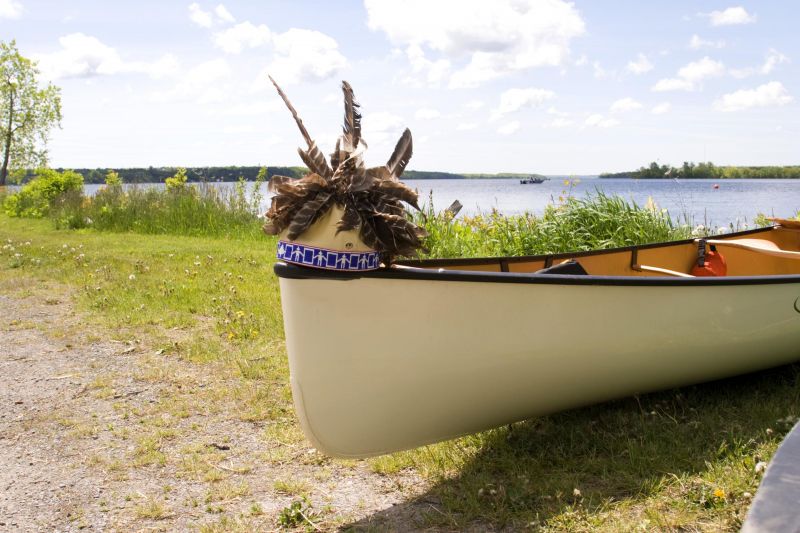 a Gustoweh headdress (traditional Haudenosaunee hat with feathers on top) sitting on the edge of a canoe