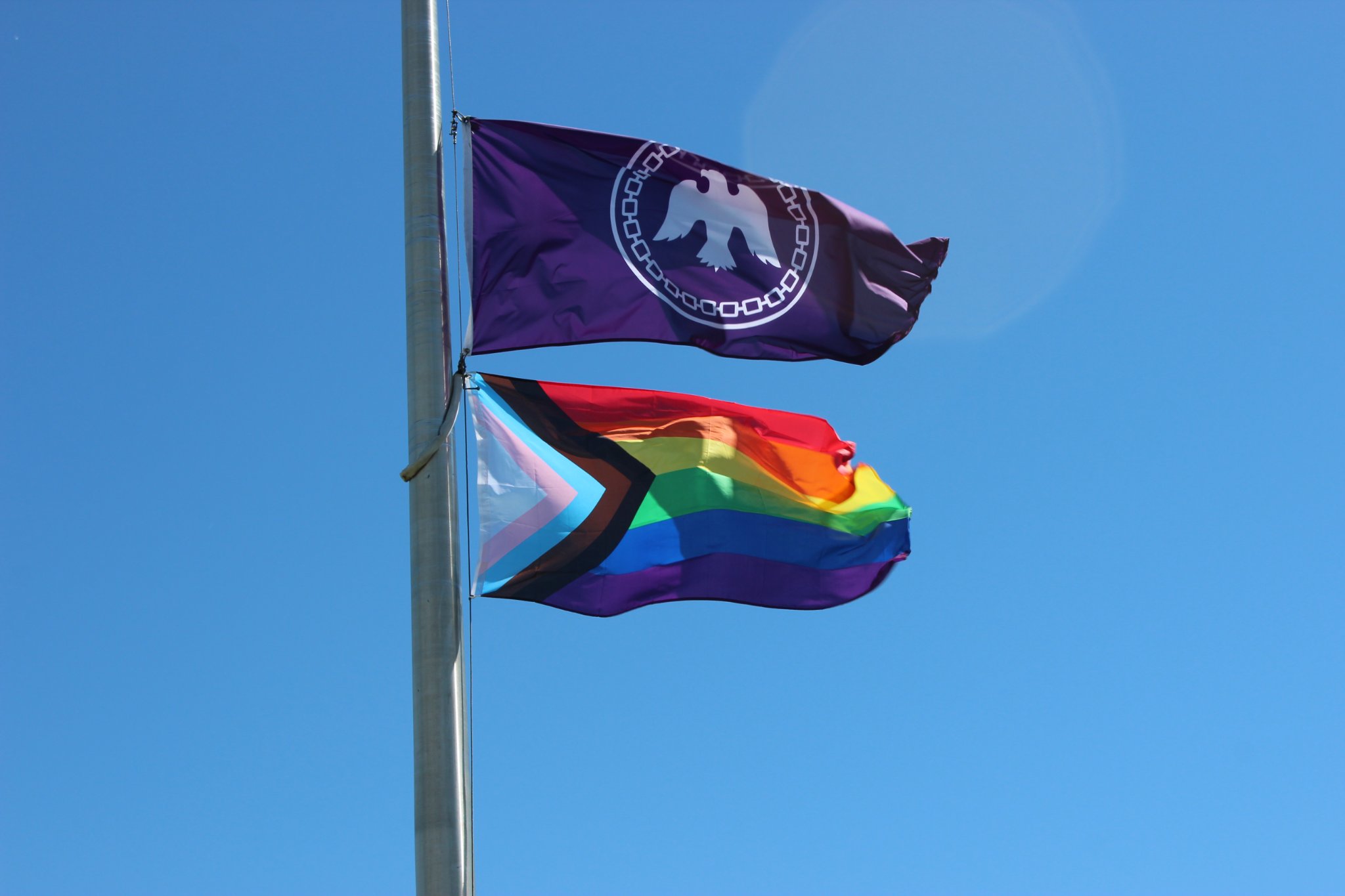 a pride flag and mohawks of the bay of quinte flag on the same flag post