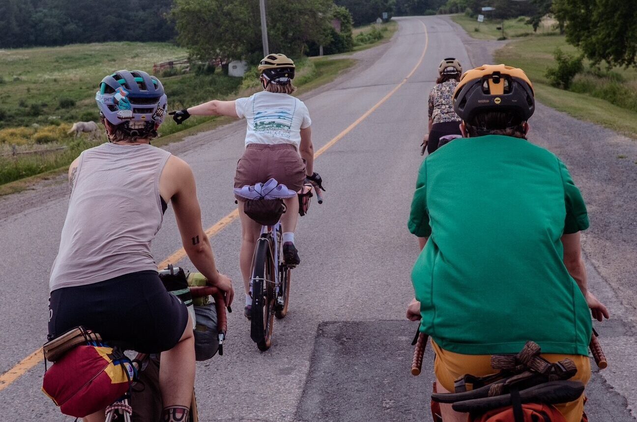 four cyclists riding along a back road in the country