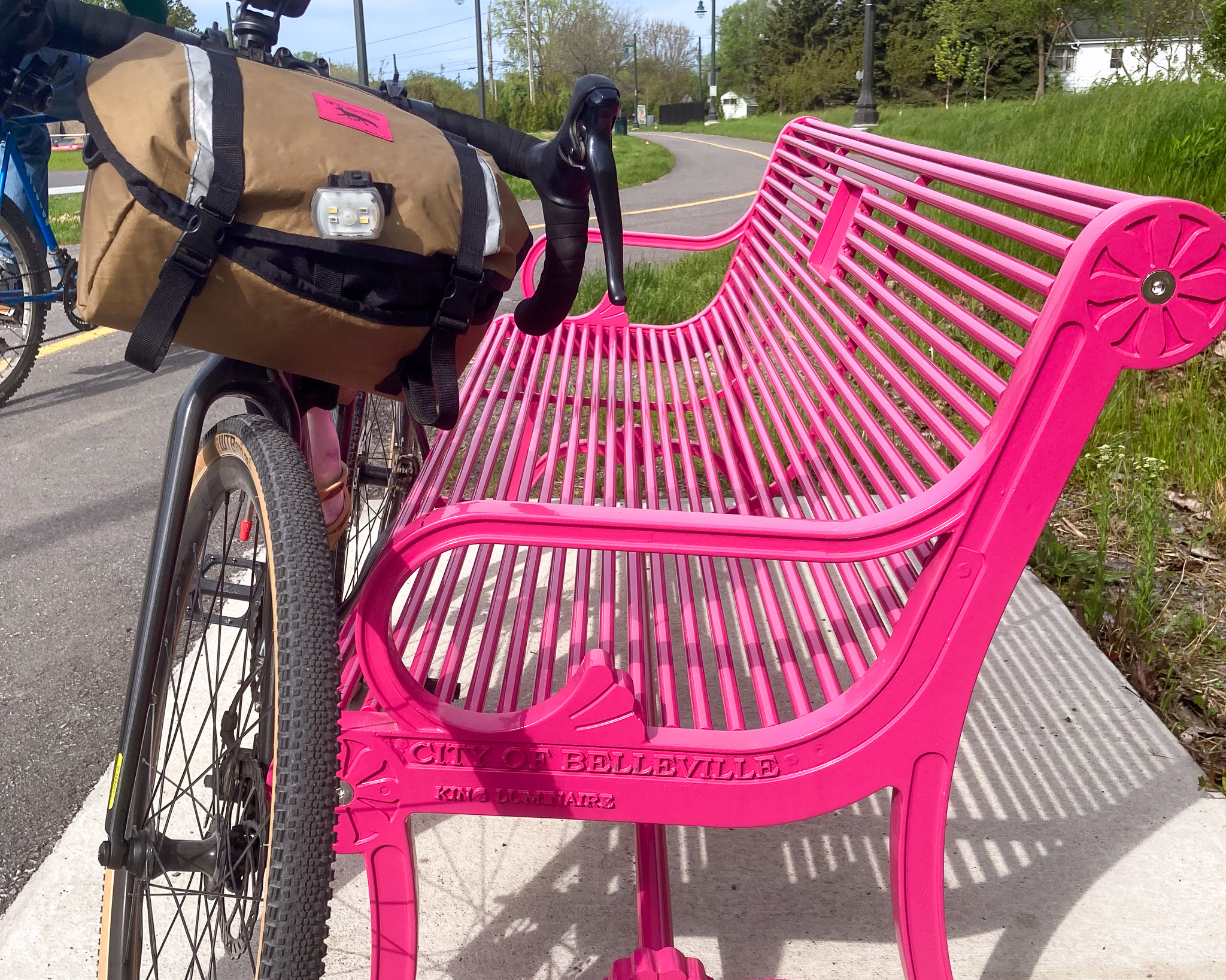 a bicycle leaning up against a hot pink park bench