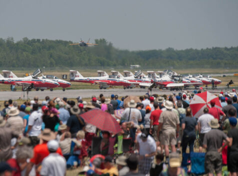 a crowd of air show attendees watching the planes lining up on the runway