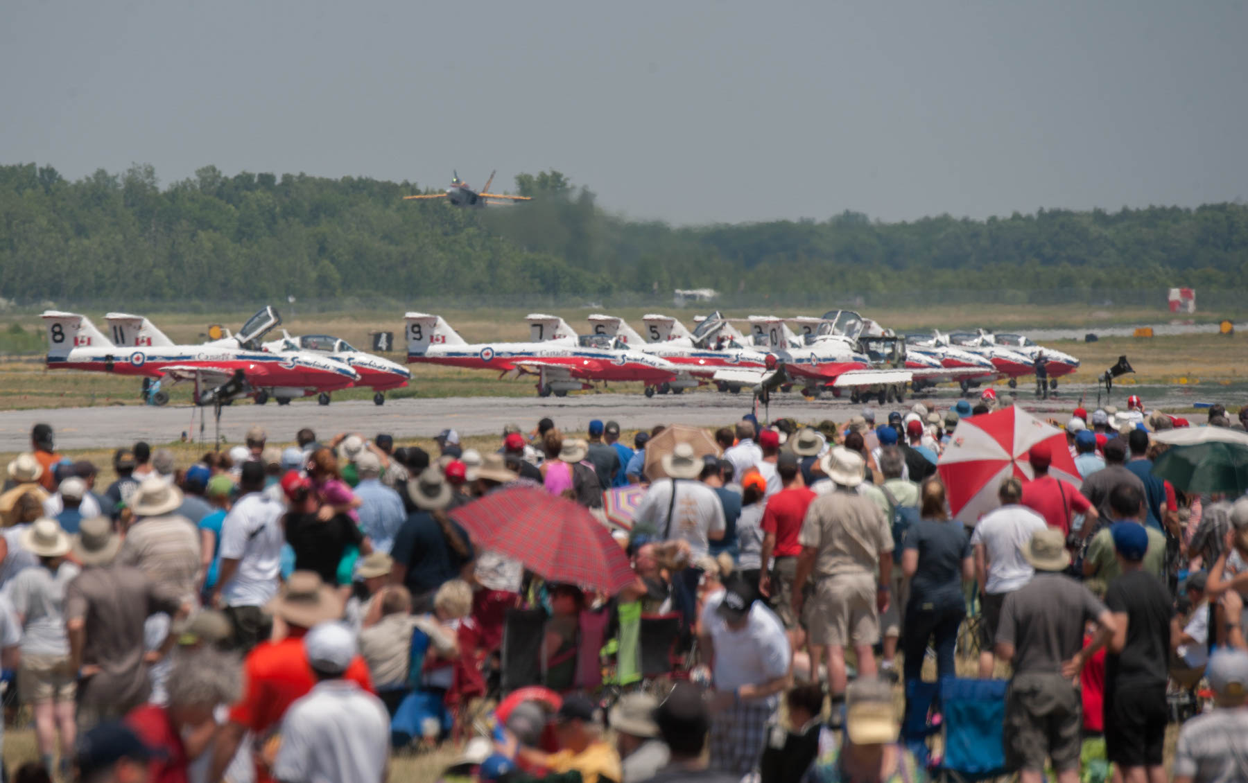 a crowd of air show attendees watching the planes lining up on the runway