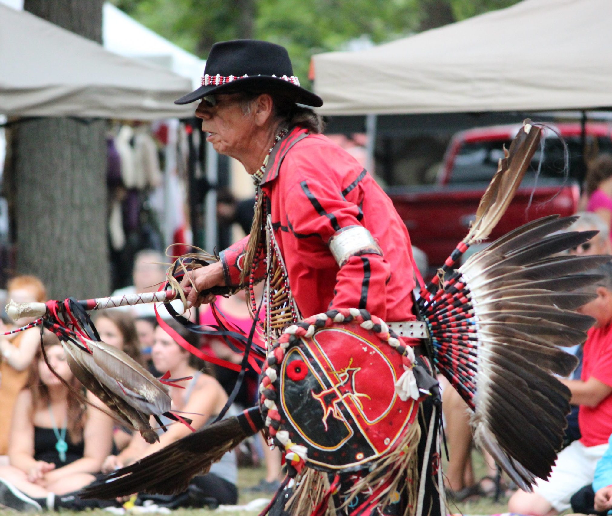 A man dances at a Pow Wow wearing traditional regalia.