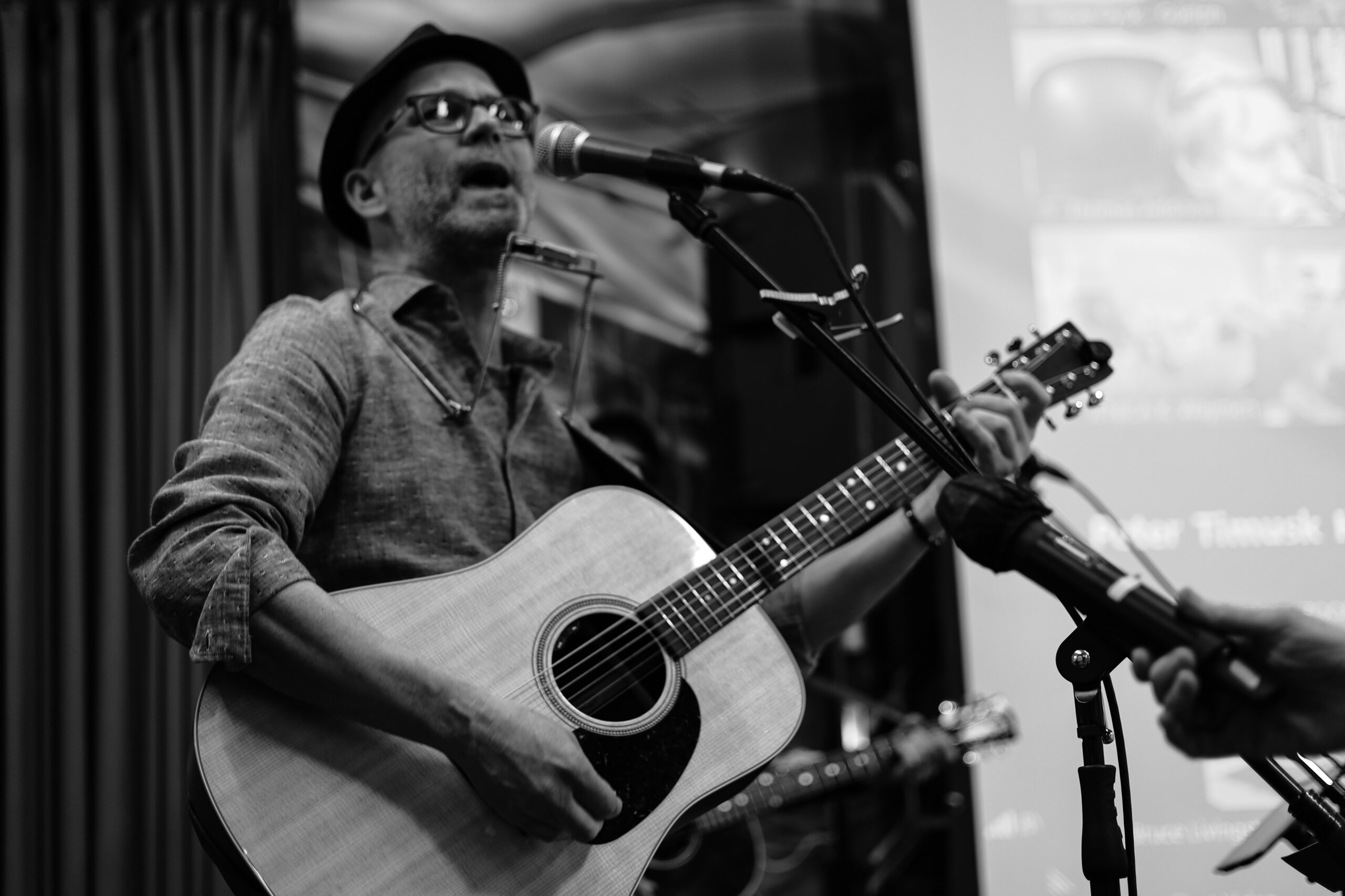 Black and white photo of musician performing with acoustic guitar.