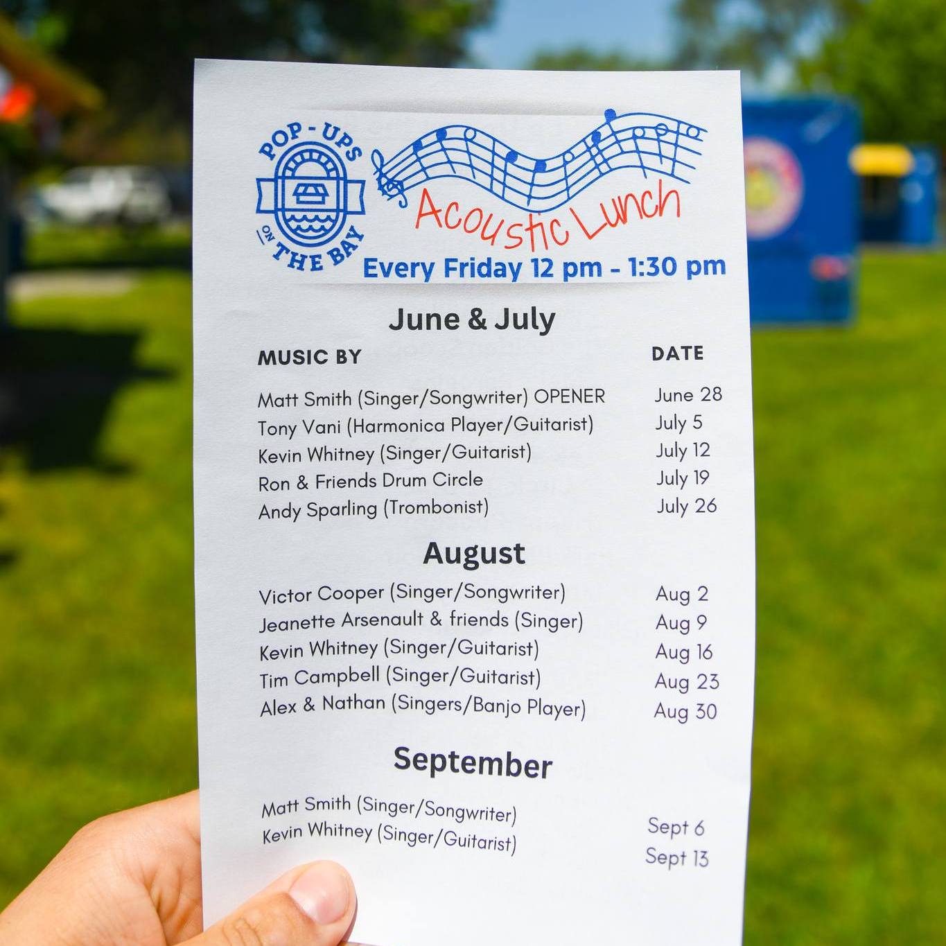 Photo of a paper schedule being held in a park setting.