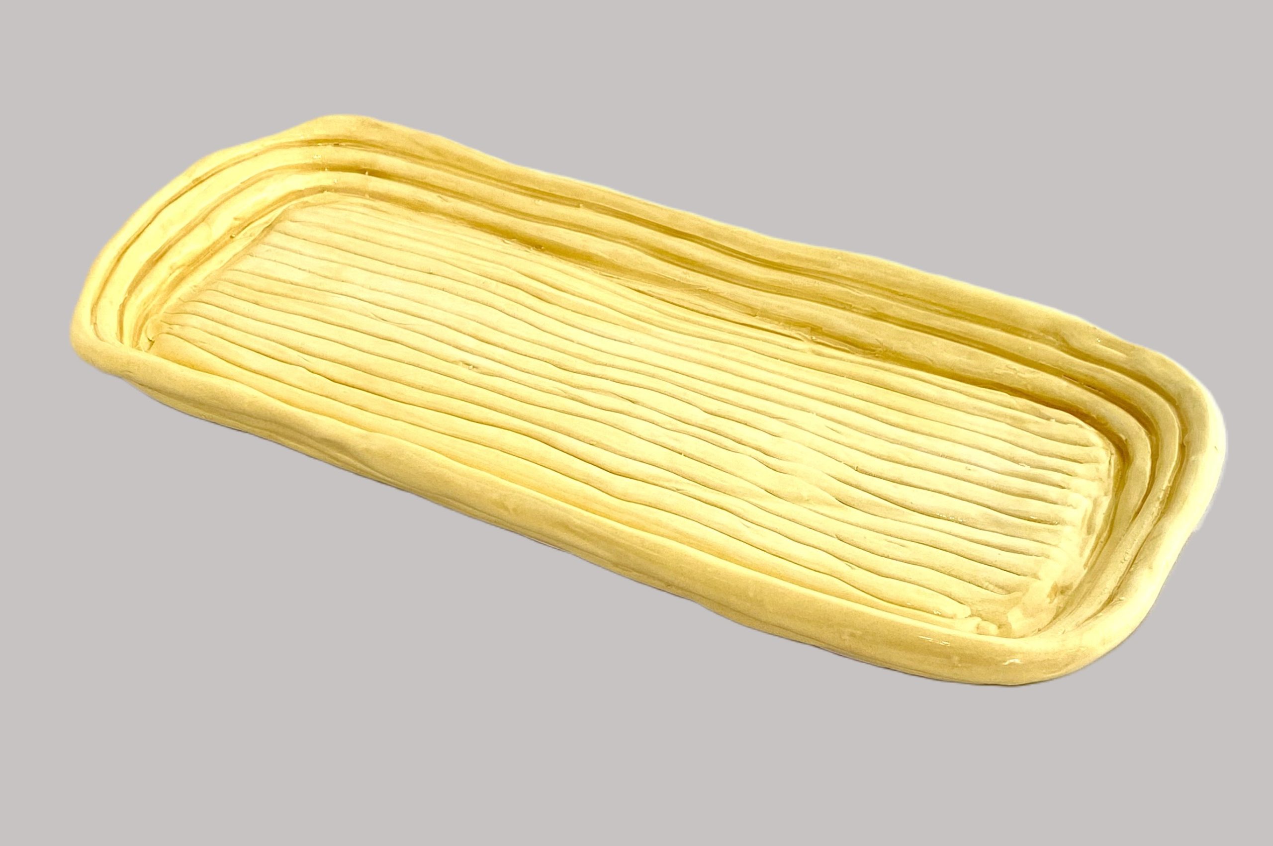 Photo of a yellow clay coil tray.