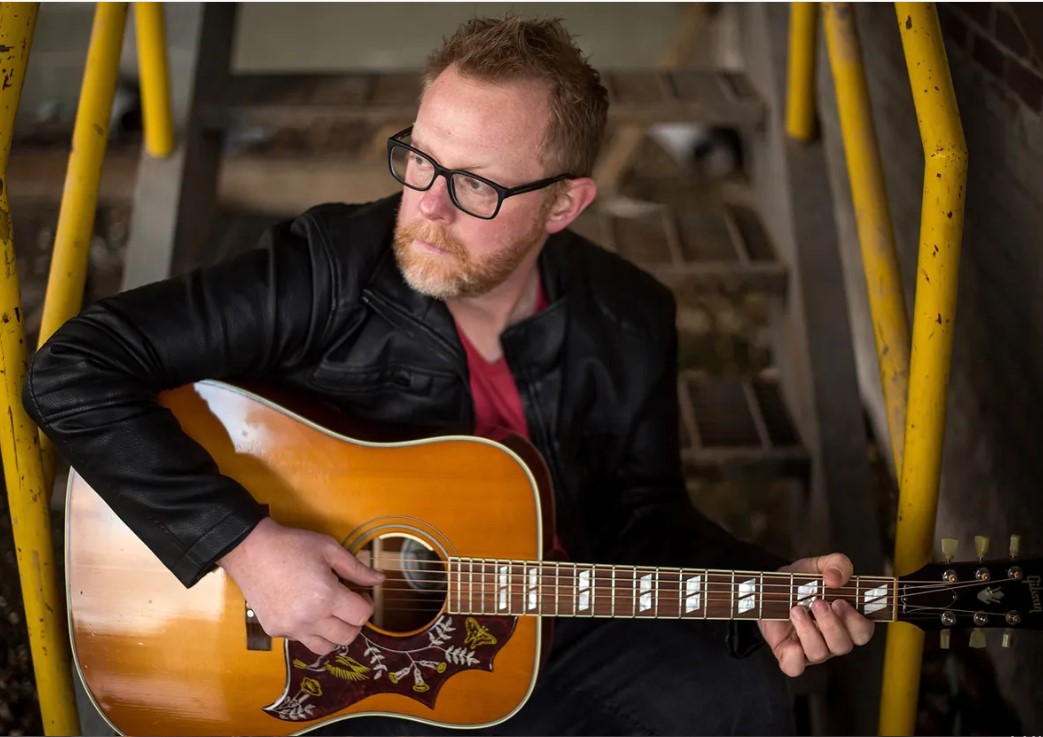 Photo of Gerald with an acoustic guitar